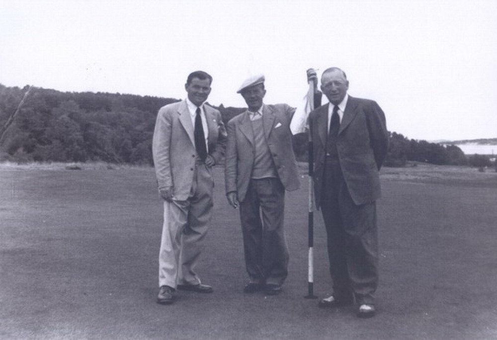 Douglas Brasier beside the pin with two fellow golfers